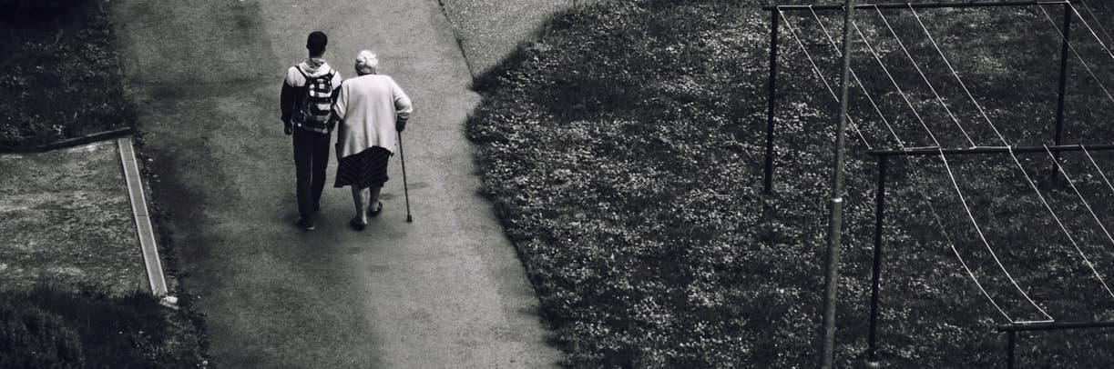 A person walking arm in arm with an older woman along a path